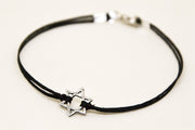 Black cord bracelet with a silver star charm on a white background