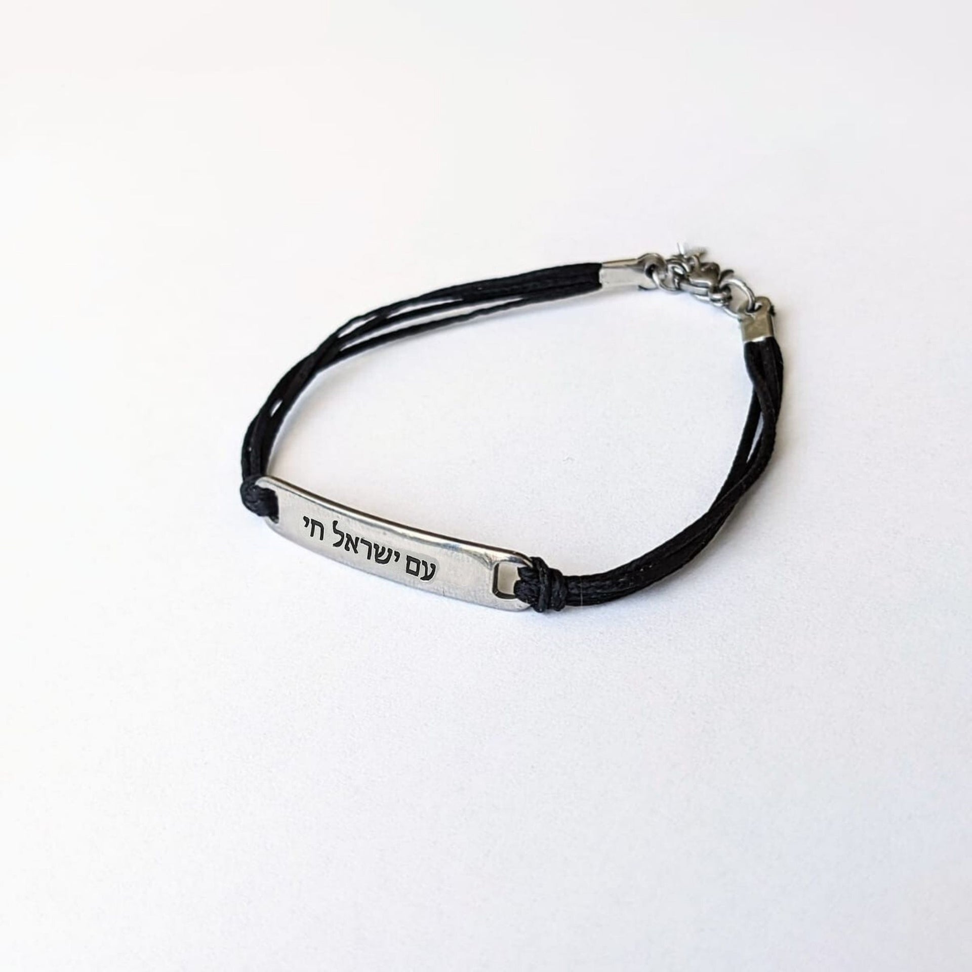 Black cord bracelet with silver tag on a white background