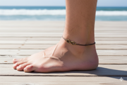 Anchored foot with an infinity anklet on a wooden deck by the ocean.