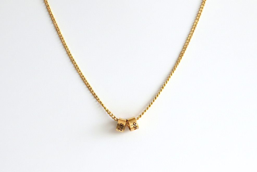 Gold necklace with a small round pendant on a white background
