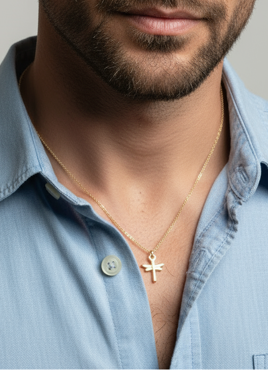 Man wearing dragonfly necklace a light blue shirt with a neutral background