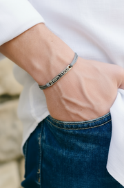 Person wearing a bracelet with a blurred stone wall background