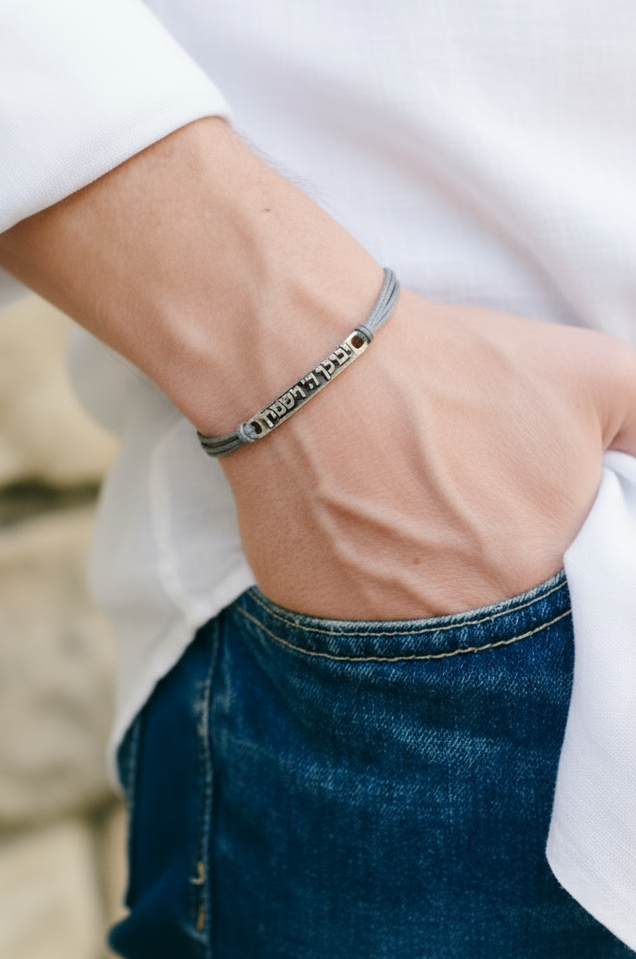 Person wearing a bracelet with a blurred stone wall background