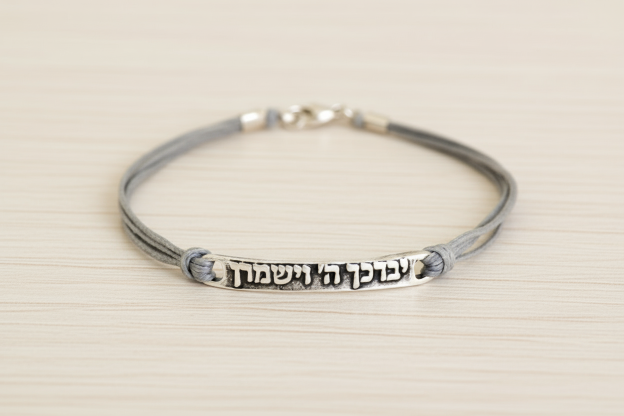 Silver bracelet with engraved Hebrew text on a beige background
