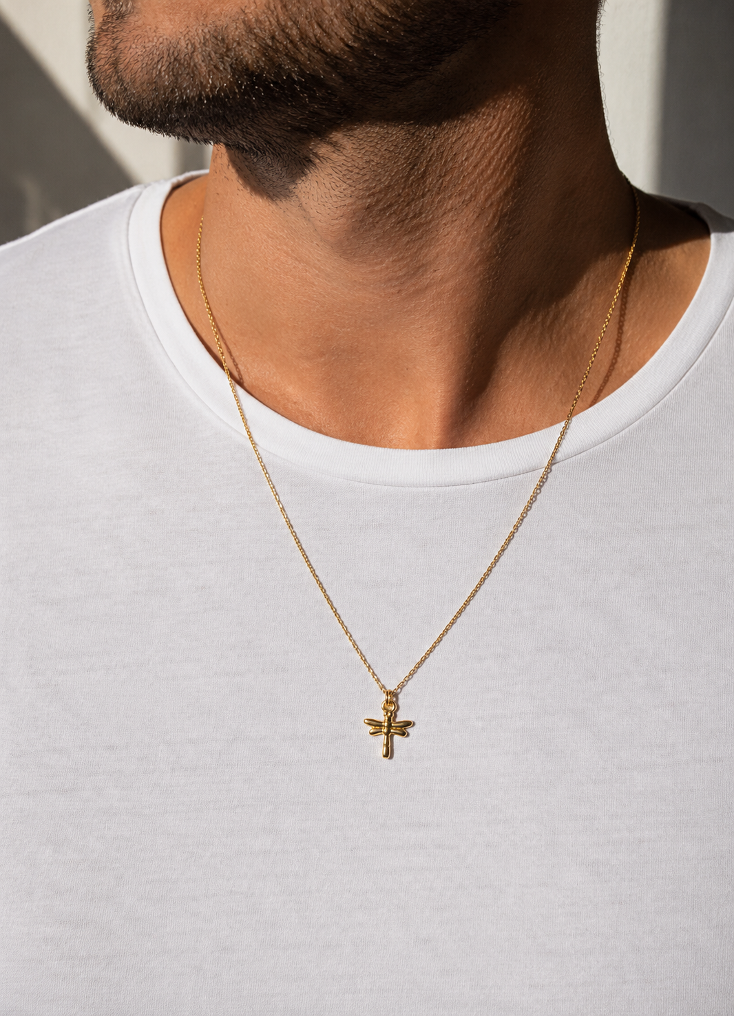 Gold necklace with a dragonfly pendant on a white background