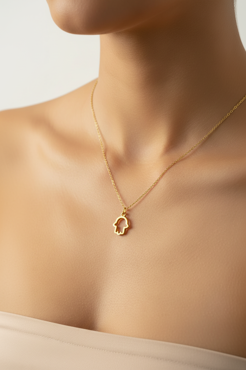 Gold necklace with a hamsa small pendant on a person's neck against a neutral background
