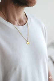 Man wearing a gold necklace with a lotus pendant