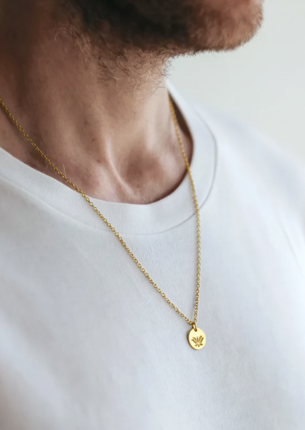 Man wearing a gold necklace with a lotus pendant