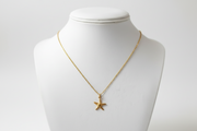 Gold necklace with a starfish pendant on a mannequin bust against a white background