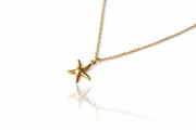 Gold starfish pendant necklace on a white background