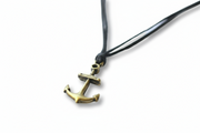 Brass anchor pendant on a black cord against a white background