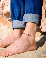 Man wearing a anchor anklet on a rocky surface