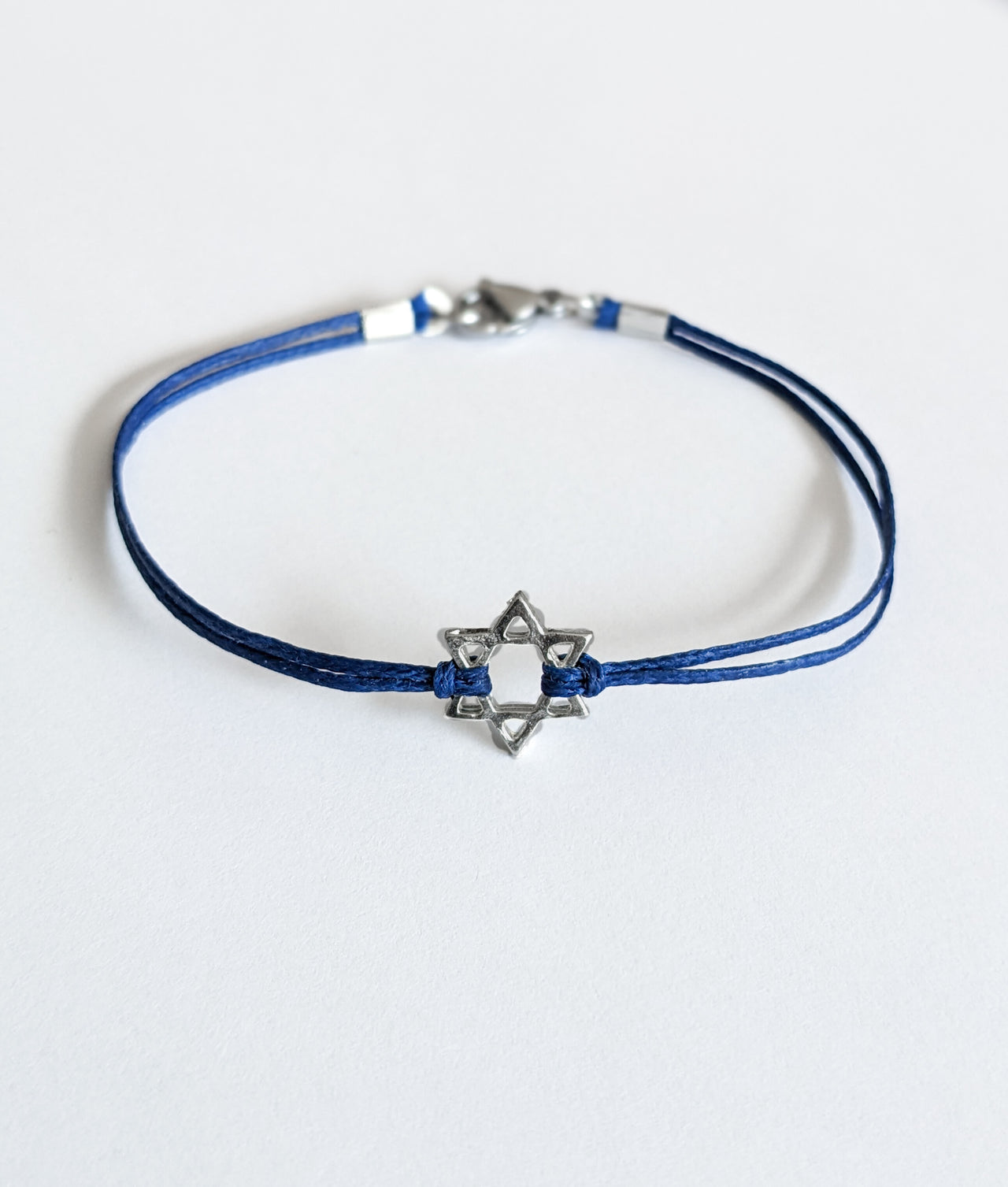 Blue bracelet with a silver Star of David charm on a white background