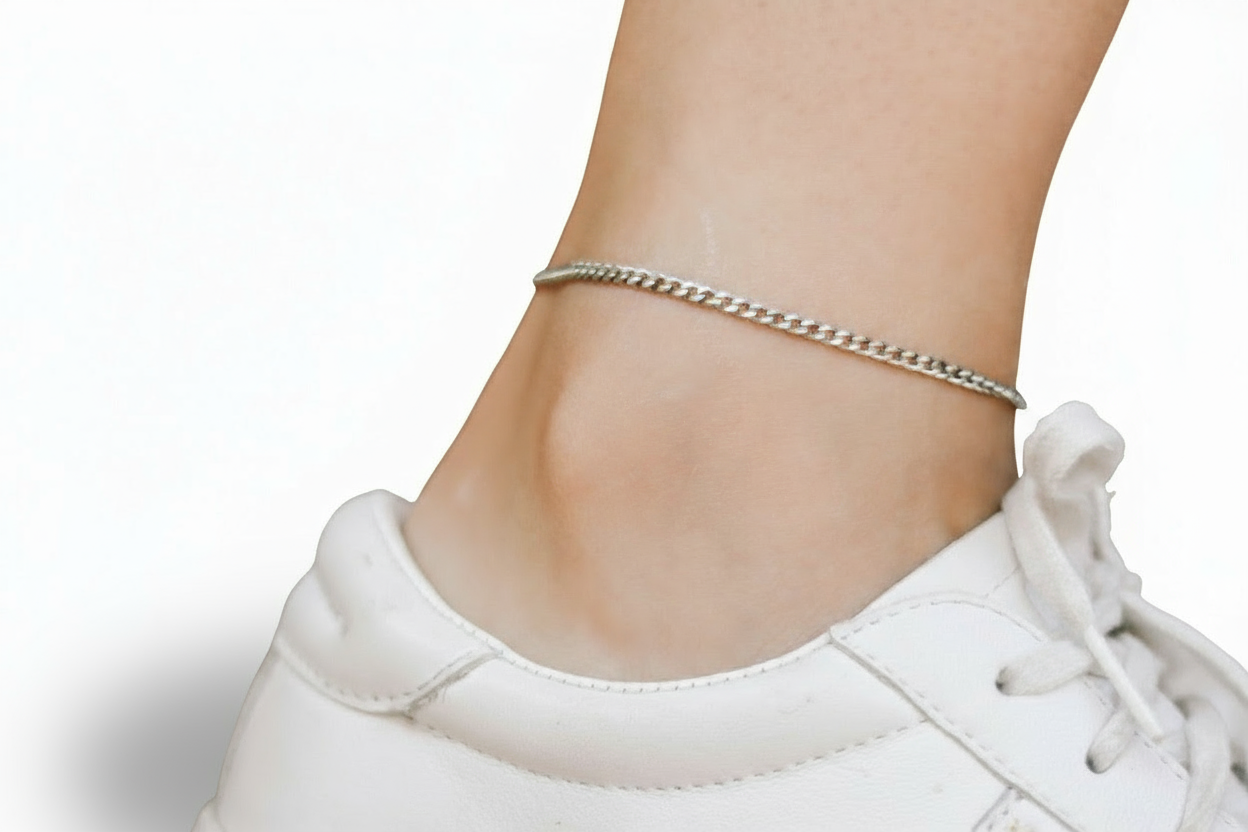 Silver chain anklet on a person's ankle with a white sneaker