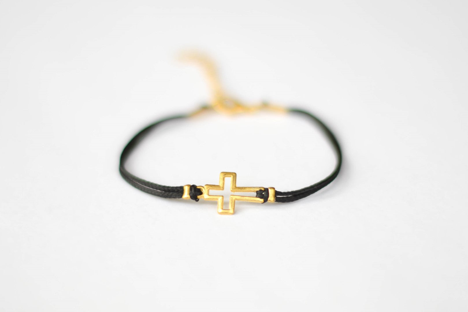 Women's bracelet with gold tone outline cross charm, black cord - shani-adi-jewerly